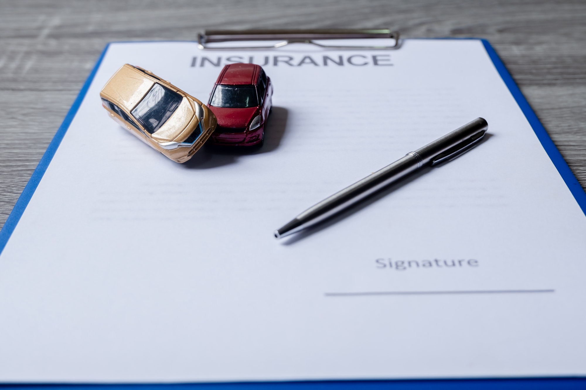 Car and pen on insurance documents. Car insurance concept.